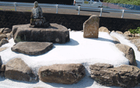 土堤上に祀ってある仏像と石碑の写真