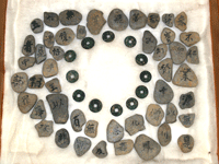 三重塔基壇出土品の川原石と小皿２枚と銭貨１２枚を並べて撮っている写真